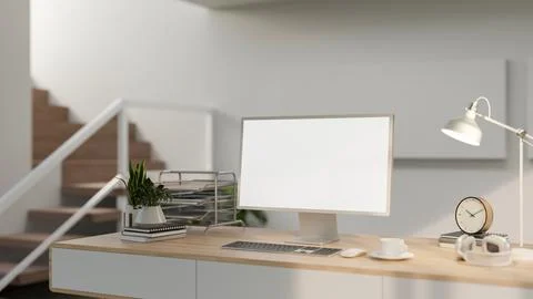 A minimalist home workspace features a computer with a white screen and obj.. Foto stock