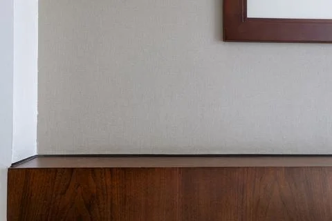 Minimalist interior composition with a textured beige wall and dark wood Stock Photos