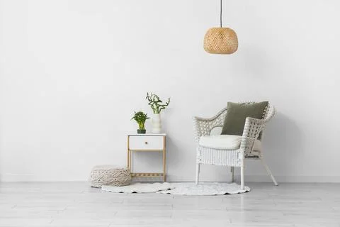 Minimalist interior design with white wicker chair, side table, plants, and w Stock Photos