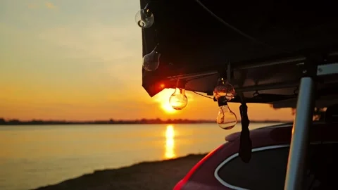 Minimalist Rooftop Camping Scene With Warm String Lights at Sunset by Water Stock Footage 324944242