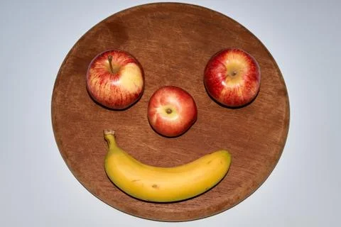 Minimalist round fruit face made of apple, peach and banana Stock Photos