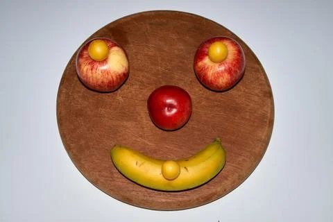 Minimalist round fruit face made of apple, peach and banana Stock Photos