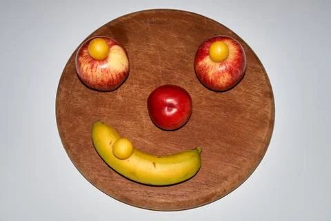 Minimalist round fruit face made of apple, peach and banana Stock Photos
