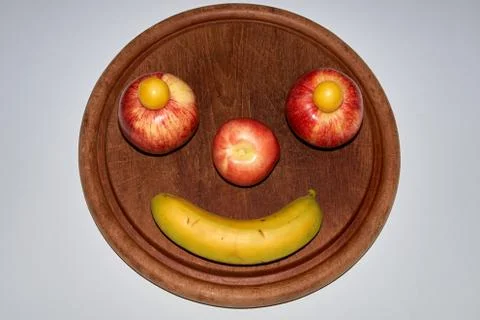 Minimalist round fruit face made of apple, peach and banana Stock Photos