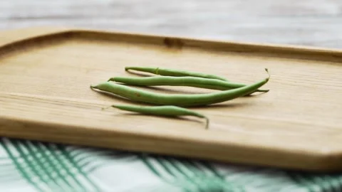 Minimalist shot of small heap of raw green beans on a chopping board Stock Footage 343555476