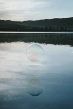Minimalist Soap Bubble Floating Above Calm Lake Water Symbolizing Balance and Stock-Fotos