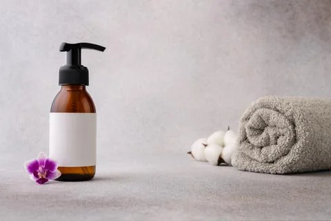 A minimalist spa setup featuring a brown pump bottle with a blank label, acco Stock Photos