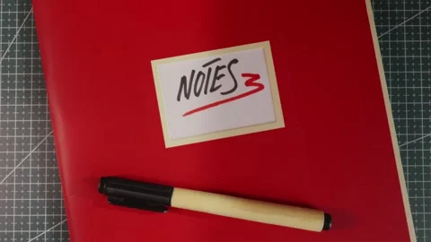 Minimalist tabletop view of red Notes journal folder Stock Footage 341269386