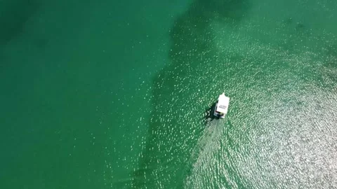 Minimalist top-down aerial drone view of a single white boat floating on crystal Stock Footage 320125320