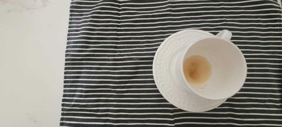 Minimalist top view of an empty white tea cup on a matching saucer over a b.. 스톡 사진