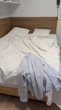 Minimalist unmade bed in cloud dancer color of the year 2026 interior vertica Stock Photos