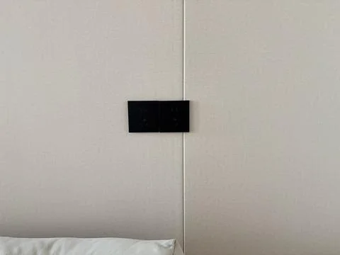 Minimalist Wall with Black Electrical Outlets Above Bed Pillow Stock-Fotos