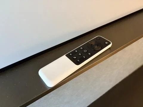 Minimalist white remote control on a dark surface. Fotos de archivo
