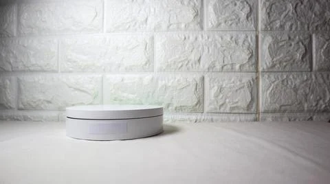 Minimalist white round device on a light surface with textured white brick .. Stock Photos