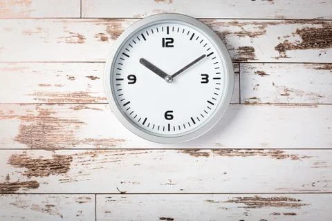 Minimalist white wall clock with light metal on wooden background texture Stock Photos