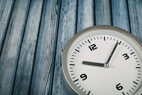 Minimalist white wall clock with light metal on wooden background texture Stock Photos