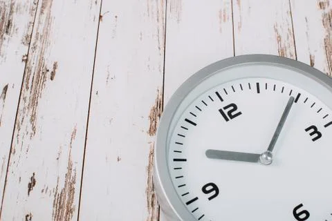 Minimalist white wall clock with light metal on wooden background texture Stock Photos