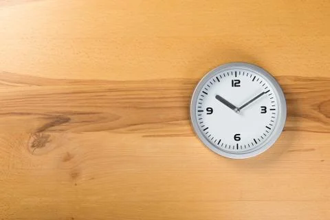 Minimalist white wall clock with light metal on wooden background texture Stock Photos