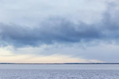 A minimalist winter seascape featuring a flat snowy shoreline Stock Photos