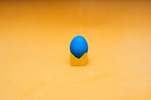 Minimalistic composition of easter egg on origami stand in the center of the Stock Photos