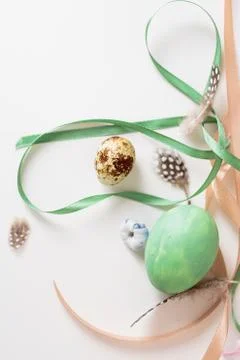 A minimalistic composition of ribbons and Easter eggs on a white table Stock Photos