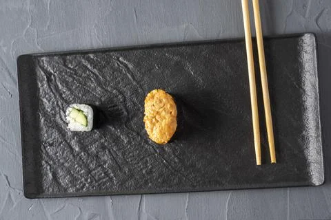 Minimalistic composition. Roll, gunkan and bamboo sticks on a textured dark p Stock Photos
