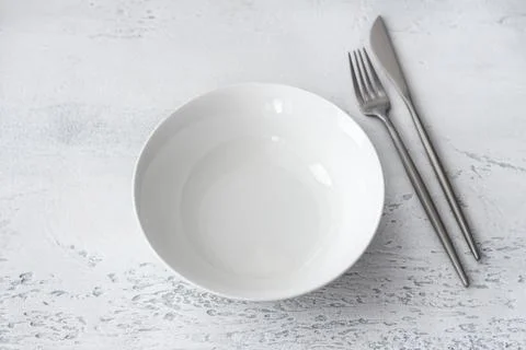 Minimalistic dining setup with white ceramic bowl and stainless steel Ccutl.. Photos