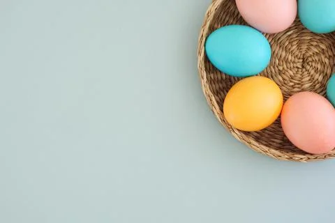 Minimalistic easter background with colored eggs in pastel shades in a basket on Stock Photos