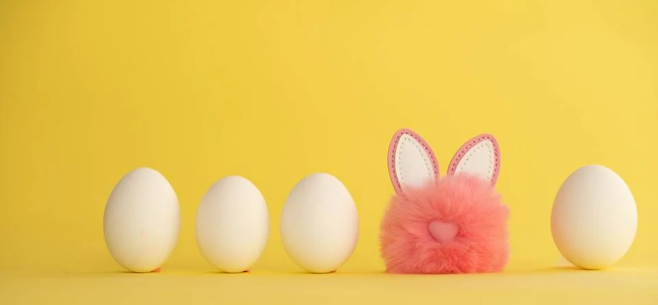 Minimalistic Easter composition. White eggs stand in a row, among them a pink Stock Photos