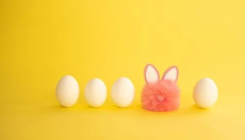 Minimalistic Easter composition. White eggs stand in a row, among them a pink Stock Photos
