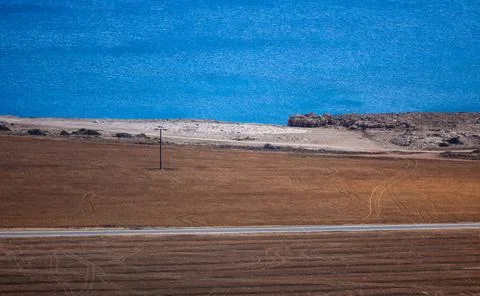 Minimalistic landscape of fields, road and sea in the background Stock Photos