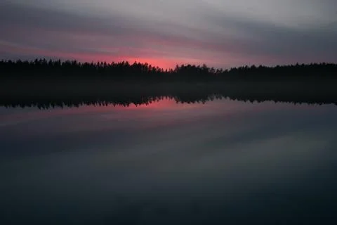 Minimalistic landscape. Mirror surface of a forest lake at sunset Stock Photos