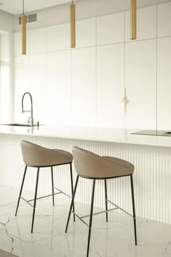 Minimalistic light interior of modern kitchen with island and high chairs Stock Photos