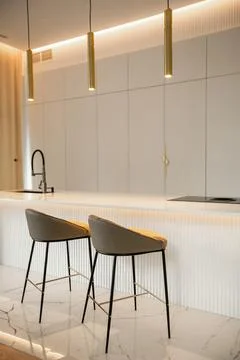 Minimalistic light interior of modern kitchen with island and high chairs Stock Photos