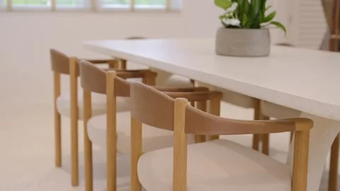 Minimalistic modern dining area with long white table surrounded by wooden Stock Footage 262274108