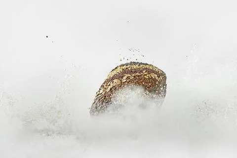 Minimalistic picture - rye bread falling into flour on a white background Stock Photos