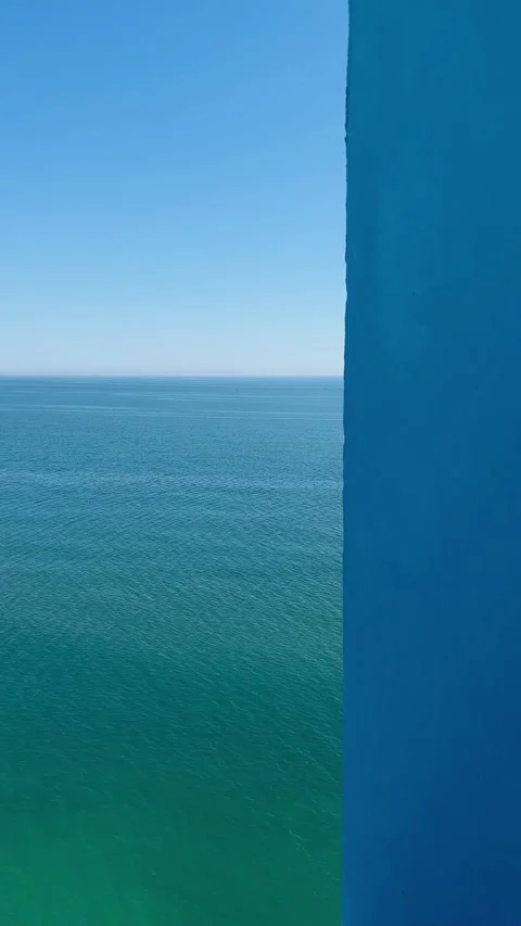 Minimalistic static shot of sea and sky behind blue wall. Vertical Stock Footage 240920063