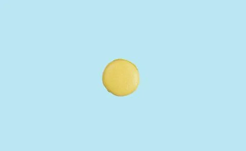 Minimalistic summer background with yellow macaroon cake in the center of the Stock Photos