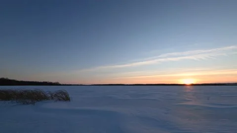 A minimalized winter sunset scene at a large pond with reeds in the foreground Stock Footage 143677178