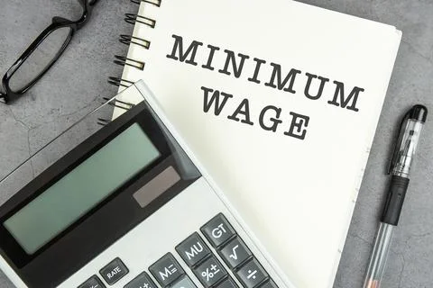 Minimum wage text on note pad with calculator. Stock Photos