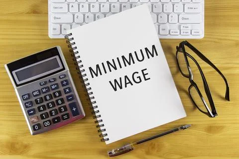 Minimum wage text on note pad with calculator. Stock Photos