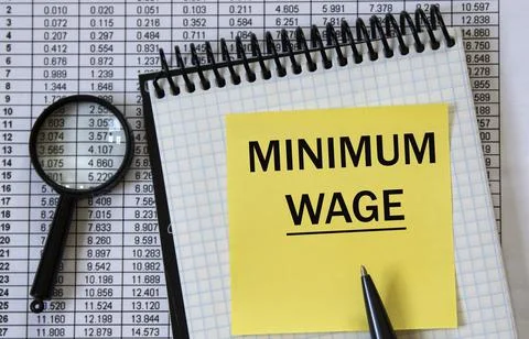 MINIMUM WAGE - words in a white notebook on the background of a table with nu Stock Photos