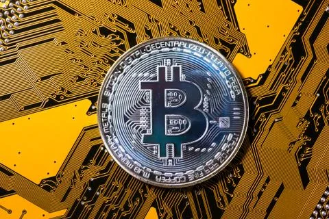 Mining Bitcoin concept - silver coin on a yellow PCB Stock Photos