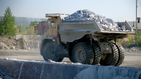 The mining dump truck backs up and pours the stone into the bunker. Back view Stock Footage 212365314