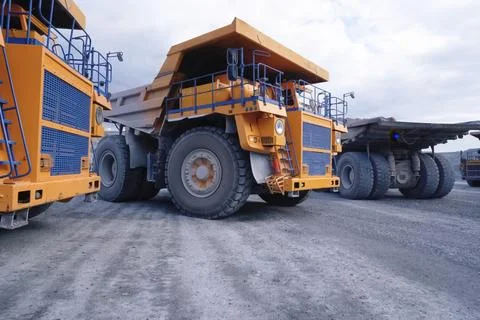 Mining dump trucks are parked in row. Equipment for an industrial quarry. Stock Photos