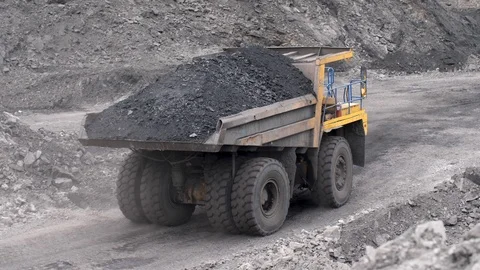 Mining dump trucks in the open pit mine. The cargo is poured out of the truck on Stock Footage