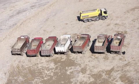 Mining dump trucks stand in line in a row at the bottom of a quarry Stock Photos