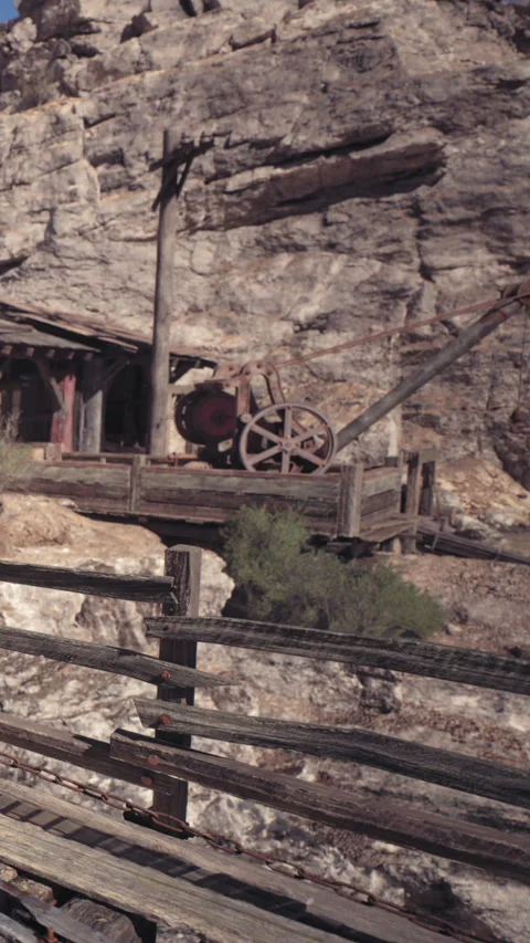 Mining equipment sits near an old wooden building in a rocky area Stock Footage 338018731