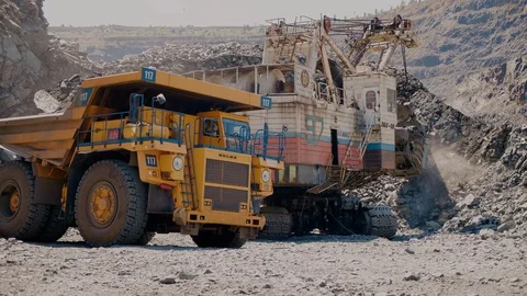 A mining excavator loads iron ore into a large dump truck Vidéo 116775680