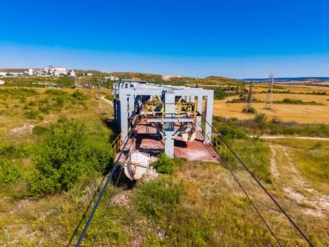 A mining machine sits at an old quarry site surrounded by green grass and ope Stock Photos